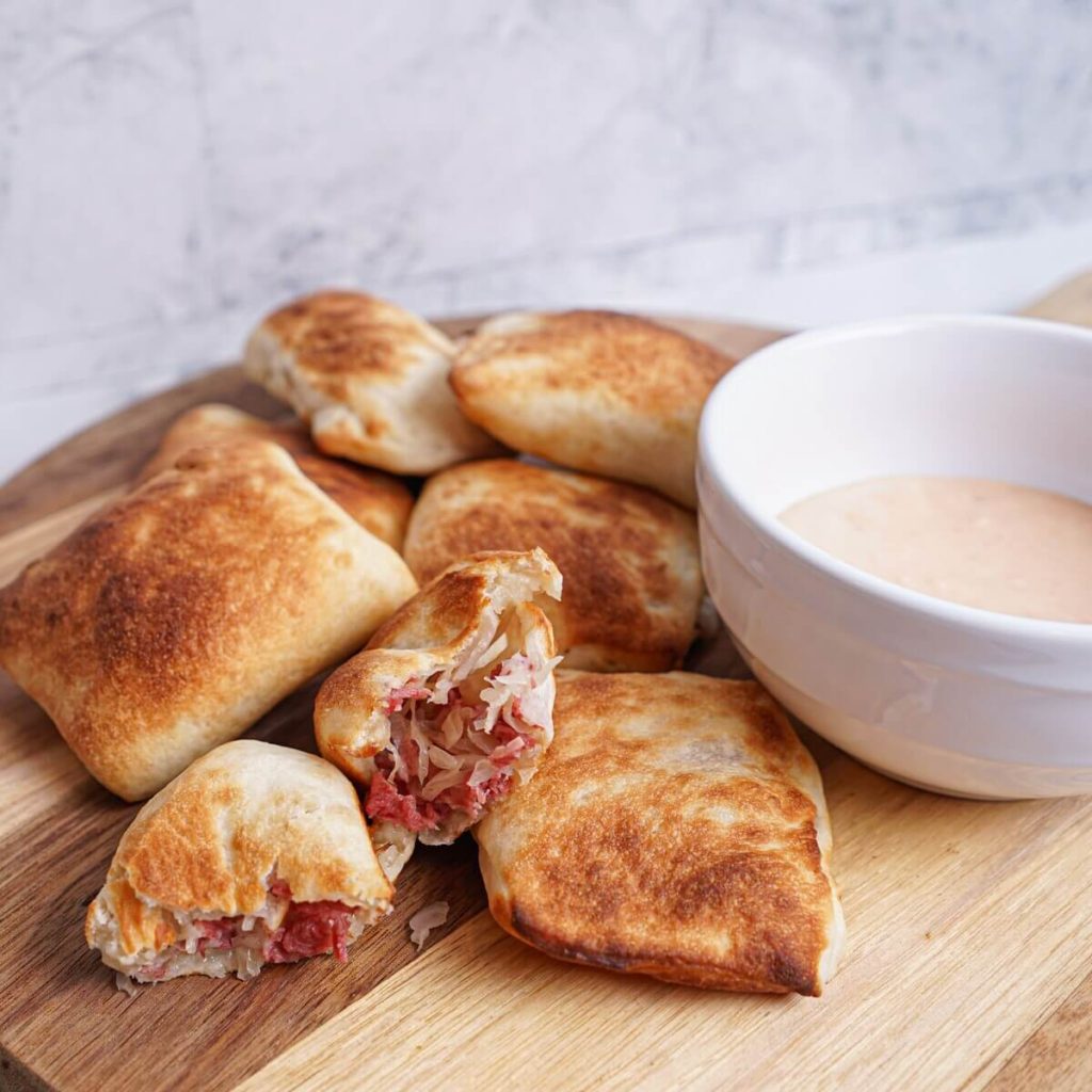 Reuben pizza rolls on cutting board with 1000 island dressing dip