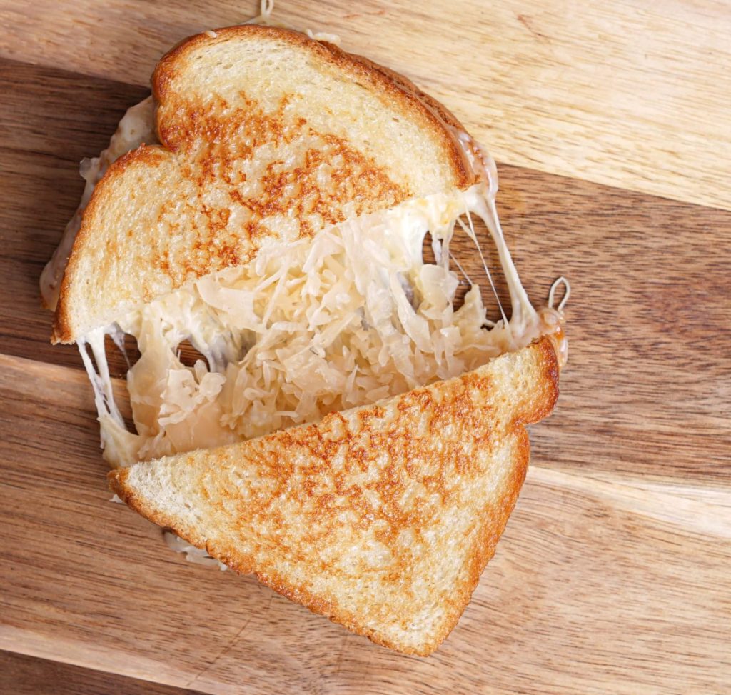 A kraut and grilled cheese sandwich on a wooden board