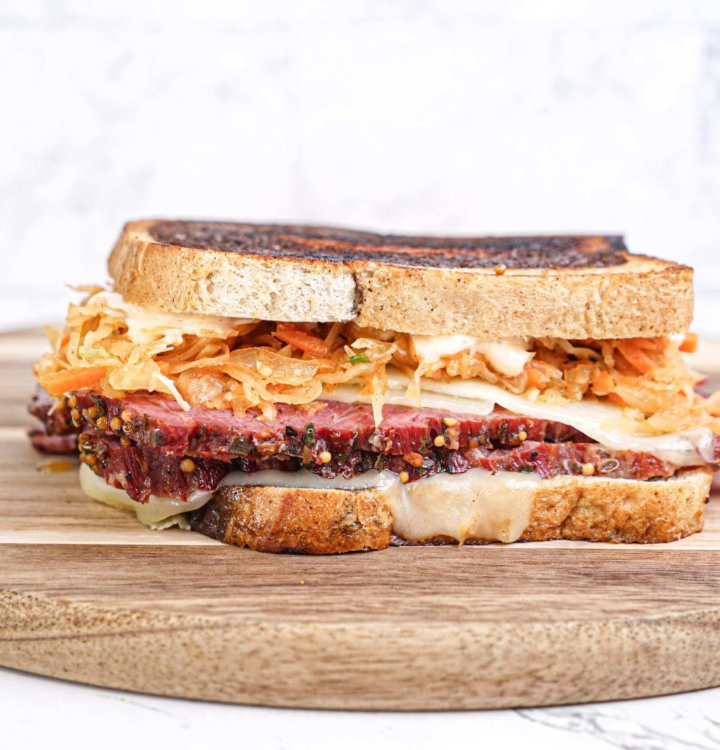 A Reuben sandwich with Kimchi on a wooden board