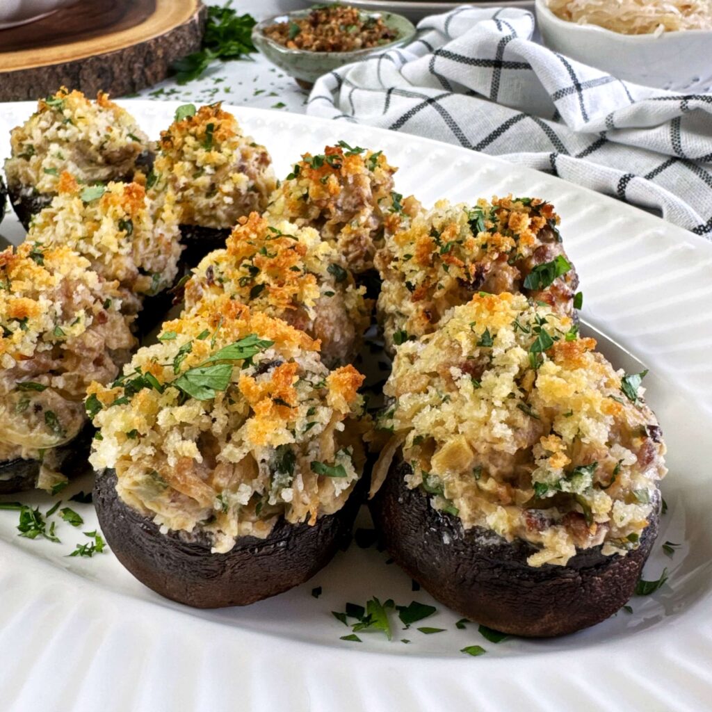 Stuffed mushrooms with sausage and kraut on a white plate.