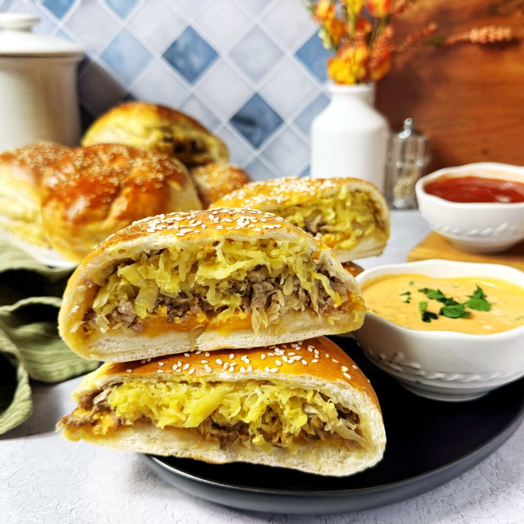 Mustard Kraut Burgers on a black plate and a cup of dipping sauce