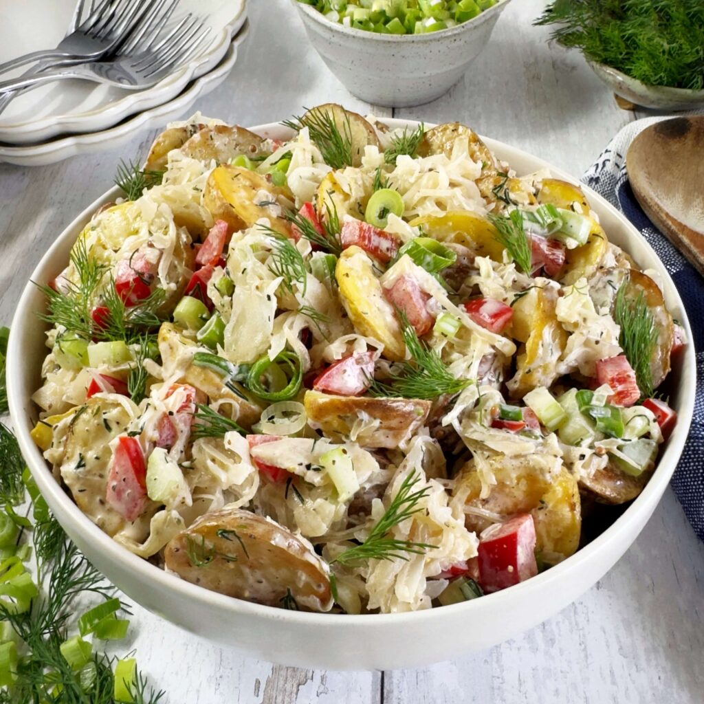 A white bowl with roasted potato Salad and Frank's Kraut