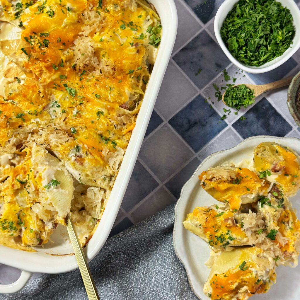 A baking dish with Pierogi inspired stuffed shells with Kielbasa and Kraut and a plate with them served on them.