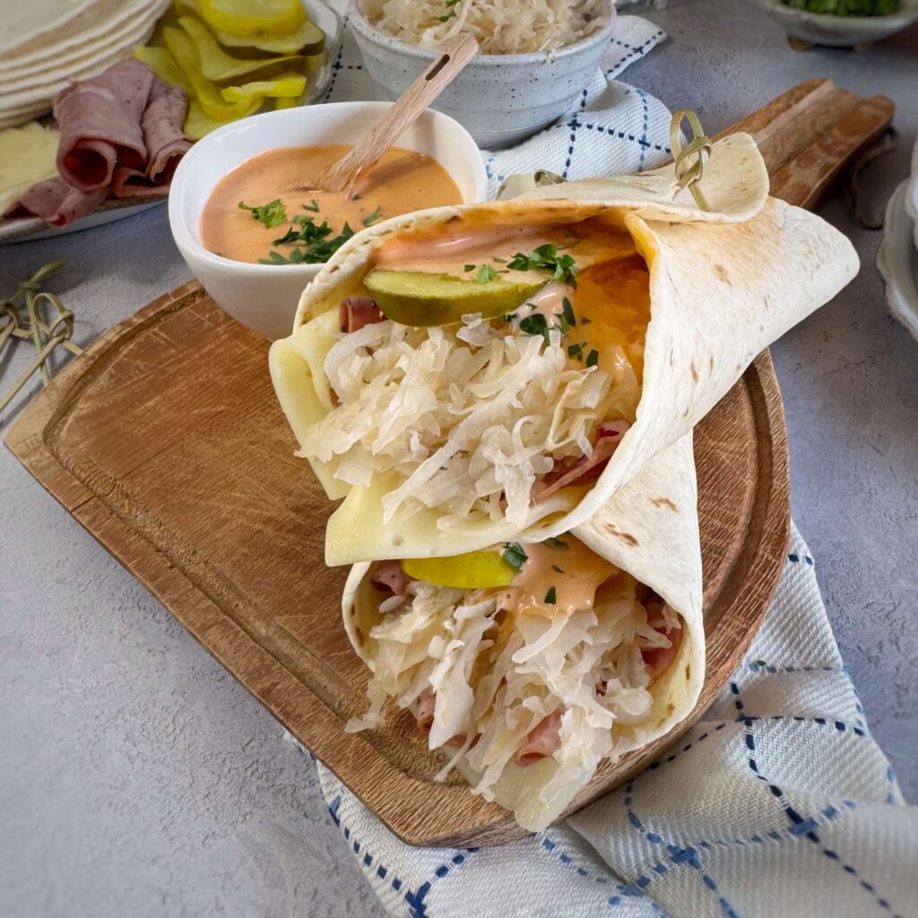 Two snack wraps on a wooden board with a small dip cup with dressing.