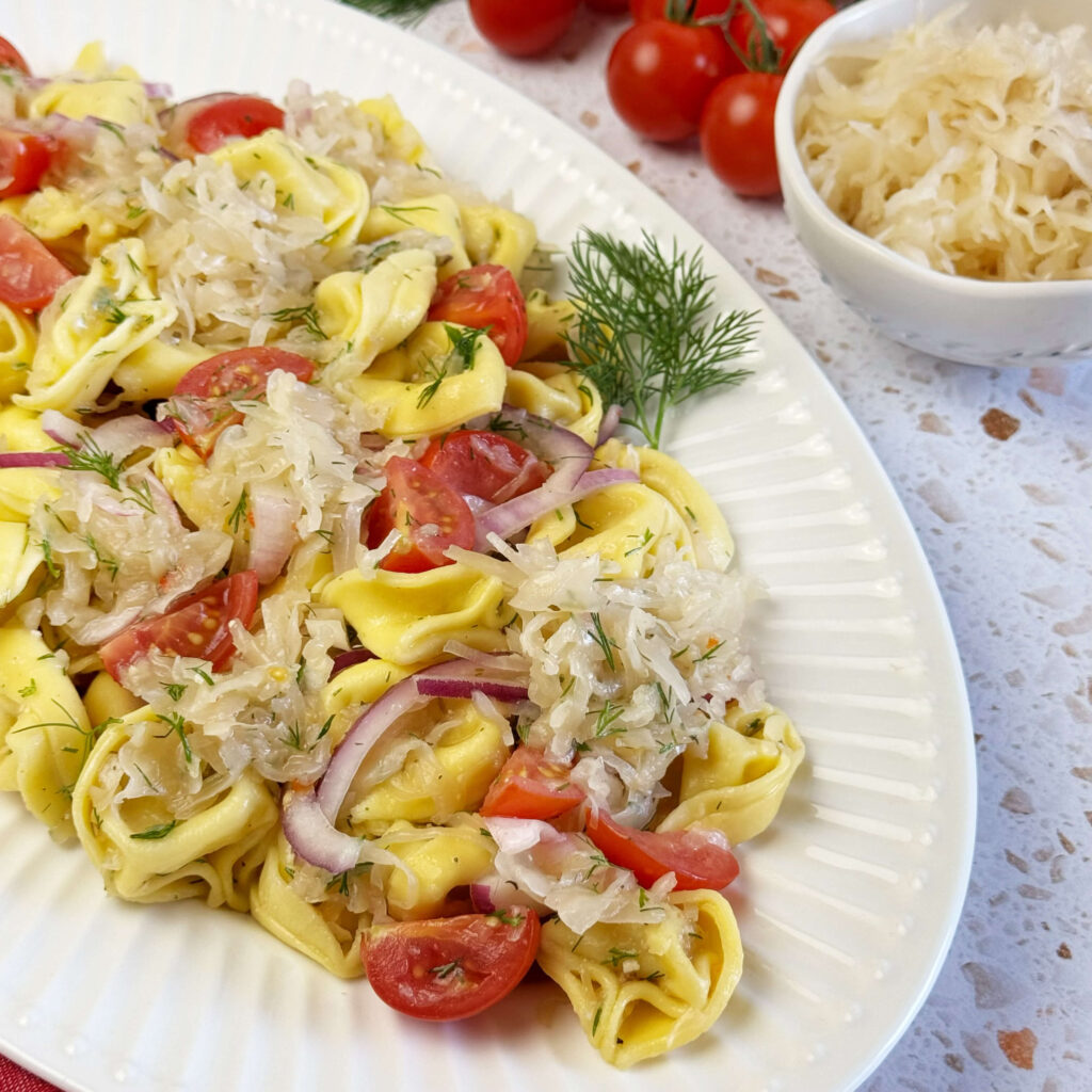 A white dinner plate with Kraut and Tortellini Pasta Salad