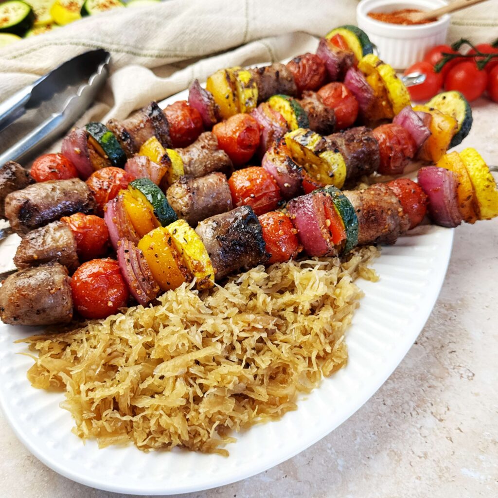 Grilled bratwurst and summer vegetable kabobs served with Frank's Sweet & Smoky BBQ Kraut for an easy backyard barbecue meal.