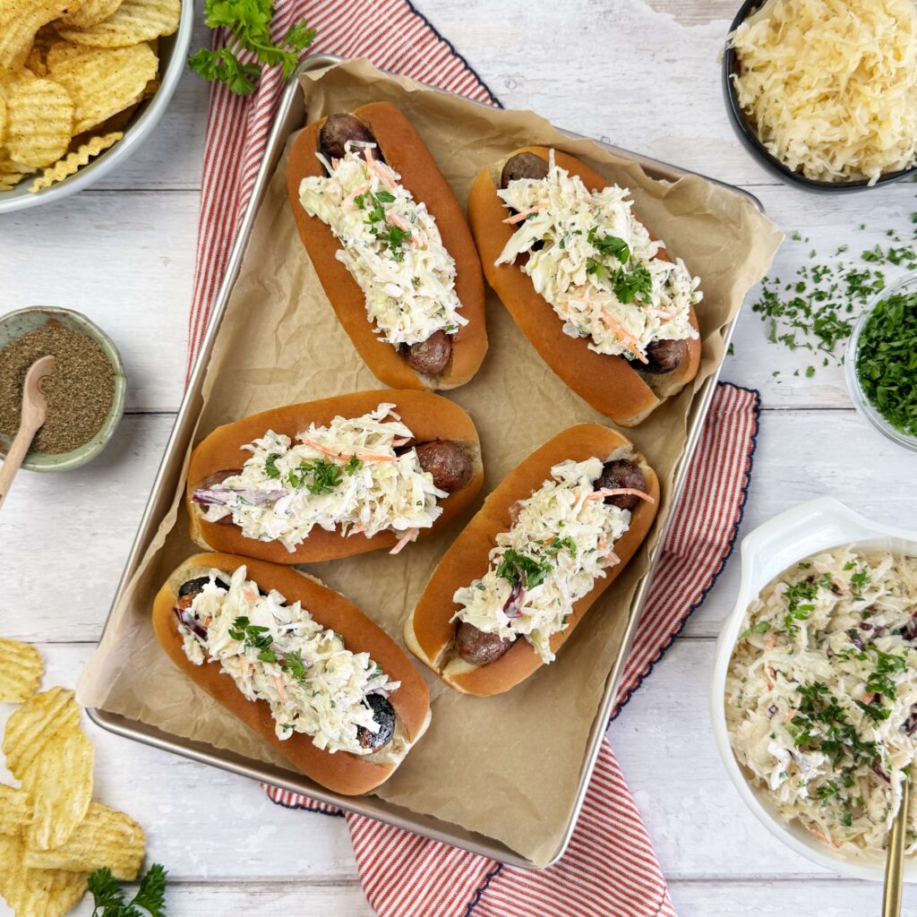 Grilled bratwursts in buns topped with creamy Frank’s Kraut coleslaw, served with potato chips.